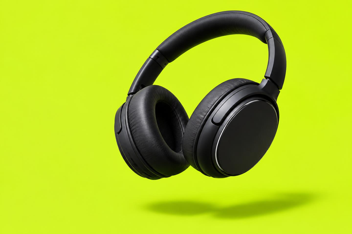 Black wireless headphones floating against a bright lime background